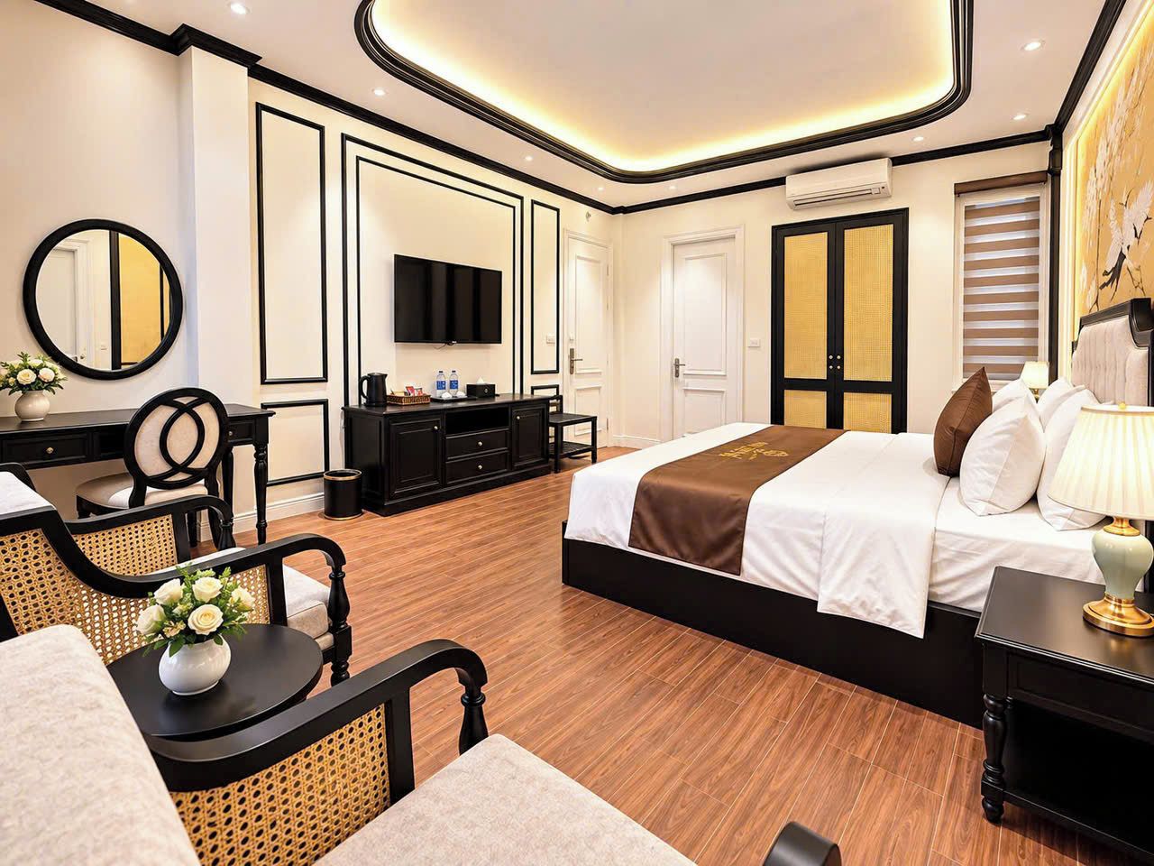 Una habitación de hotel moderna con una cama grande, un televisor de pantalla plana, un escritorio con una silla y una pequeña mesa con un jarrón de flores.