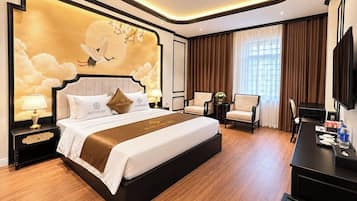 A hotel room with a large bed, a desk, a chair, a TV, and a wall with a decorative mural.