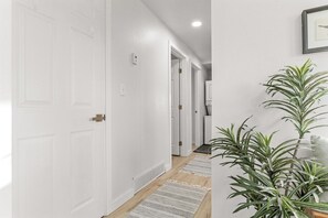 A hallway with white doors, a plant, and a framed picture on the wall. - Pet-Friendly 3-Bedroom Home in Billings, Montana (Billings)