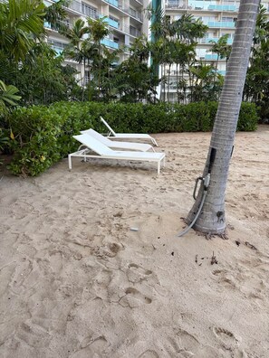 A sandy beach area with two white lounge chairs and a palm tree. - Ilikai Marina condo for rent with free parking (Honolulu)