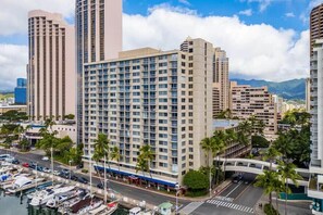 Ein hoch aufragendes Hotel mit modernem Design, in der Nähe eines Hafens mit vor Anker liegenden Booten.
