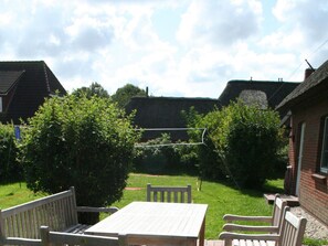 A patio with a table and chairs, surrounded by greenery and a clear sky. - Holiday Home in Borgsum With Terrace (Borgsum)