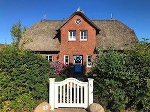 A traditional brick house with a thatched roof, a white gate, and a number '8' sign. - Holiday Home in Borgsum With Terrace (Borgsum)