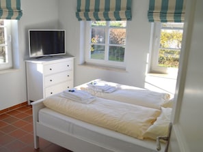 A bedroom with a bed, a TV on a dresser, and windows with curtains. - Holiday Home in Borgsum With Terrace (Borgsum)