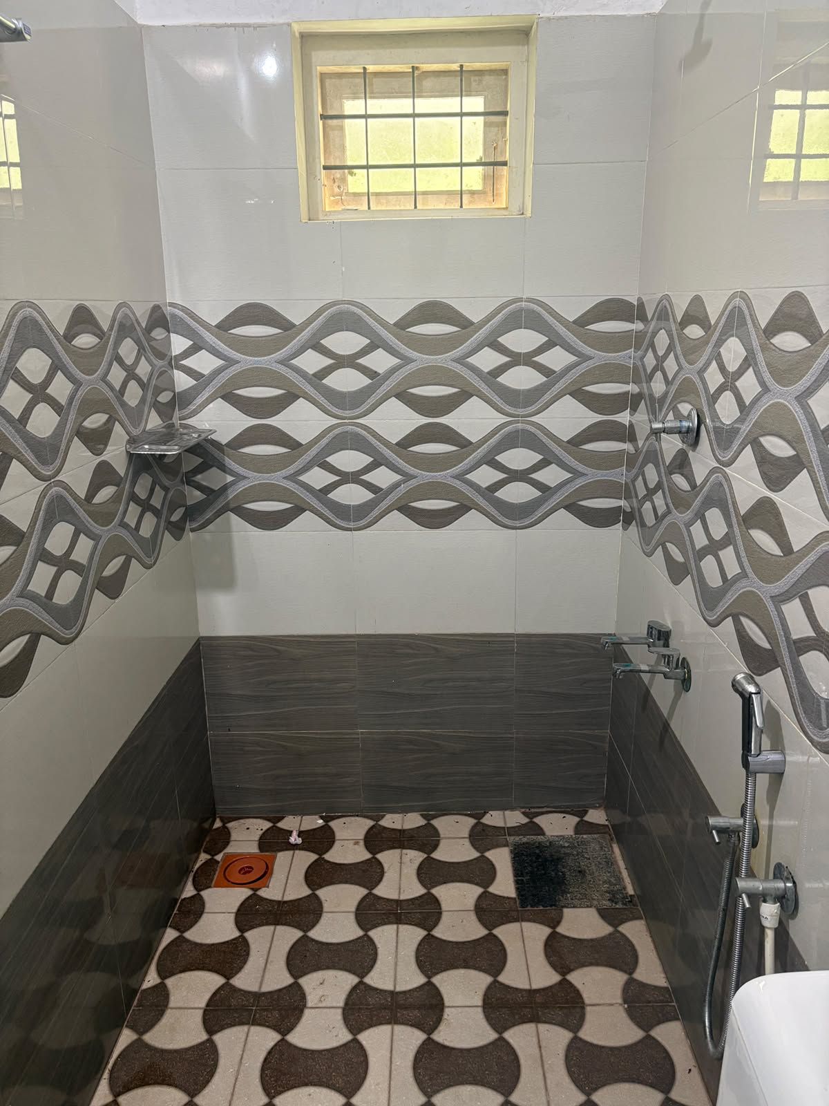 Une salle de bain avec une douche, une fenêtre et des carreaux décorés.