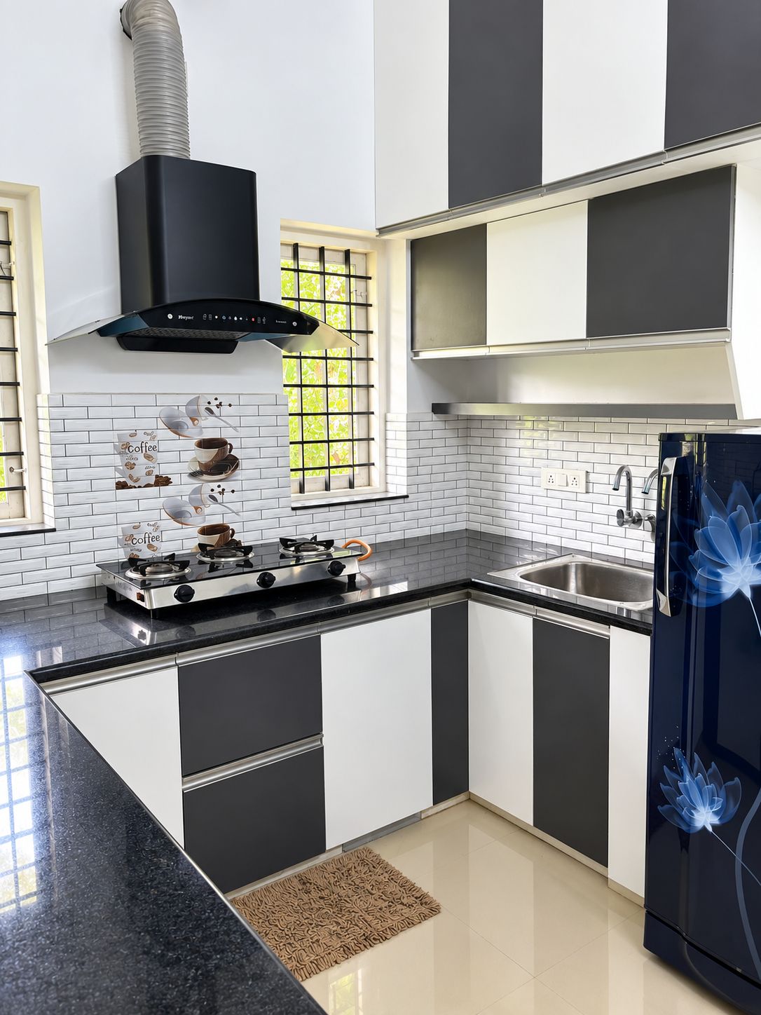 Une cuisine moderne équipée d’une cuisinière à gaz, d’un évier en acier inoxydable et de meubles de rangement noirs.