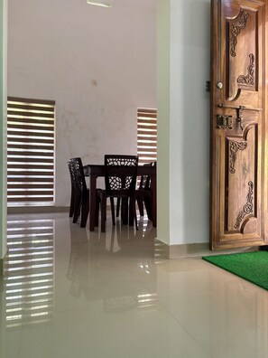 Une pièce avec une porte en bois, une table à manger avec des chaises et un tapis vert.