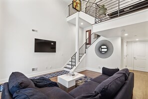 Ein modernes Wohnzimmer mit einem Flachbildfernseher, einer Treppe und einem Wanddekor.