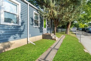 A residential property with a well-maintained lawn, a pathway leading to the entrance, and a fence along the street. - Montana Retreat Cozy, Convenient & Pet-Friendly (Billings)