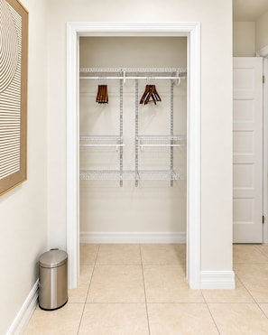 A walk-in closet with metal shelving, a trash can, and a door leading to another room. - Aqua Suites (Nassau)