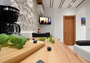 Ein modernes Wohnzimmer mit Couchtisch aus Holz, einem an der Wand montierten Fernseher und einer Tür zu einem anderen Raum.