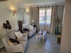 A living room with a sofa, a coffee table, and a lamp. - Cozy Vacation Rental - Porte de Chambord - Garden - Pets Allowed   (Huisseau-sur-Cosson)