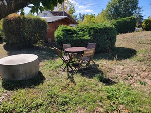 An outdoor seating area with a round table and four chairs, surrounded by grass and bushes. - Cozy Vacation Rental - Porte de Chambord - Garden - Pets Allowed   (Huisseau-sur-Cosson)