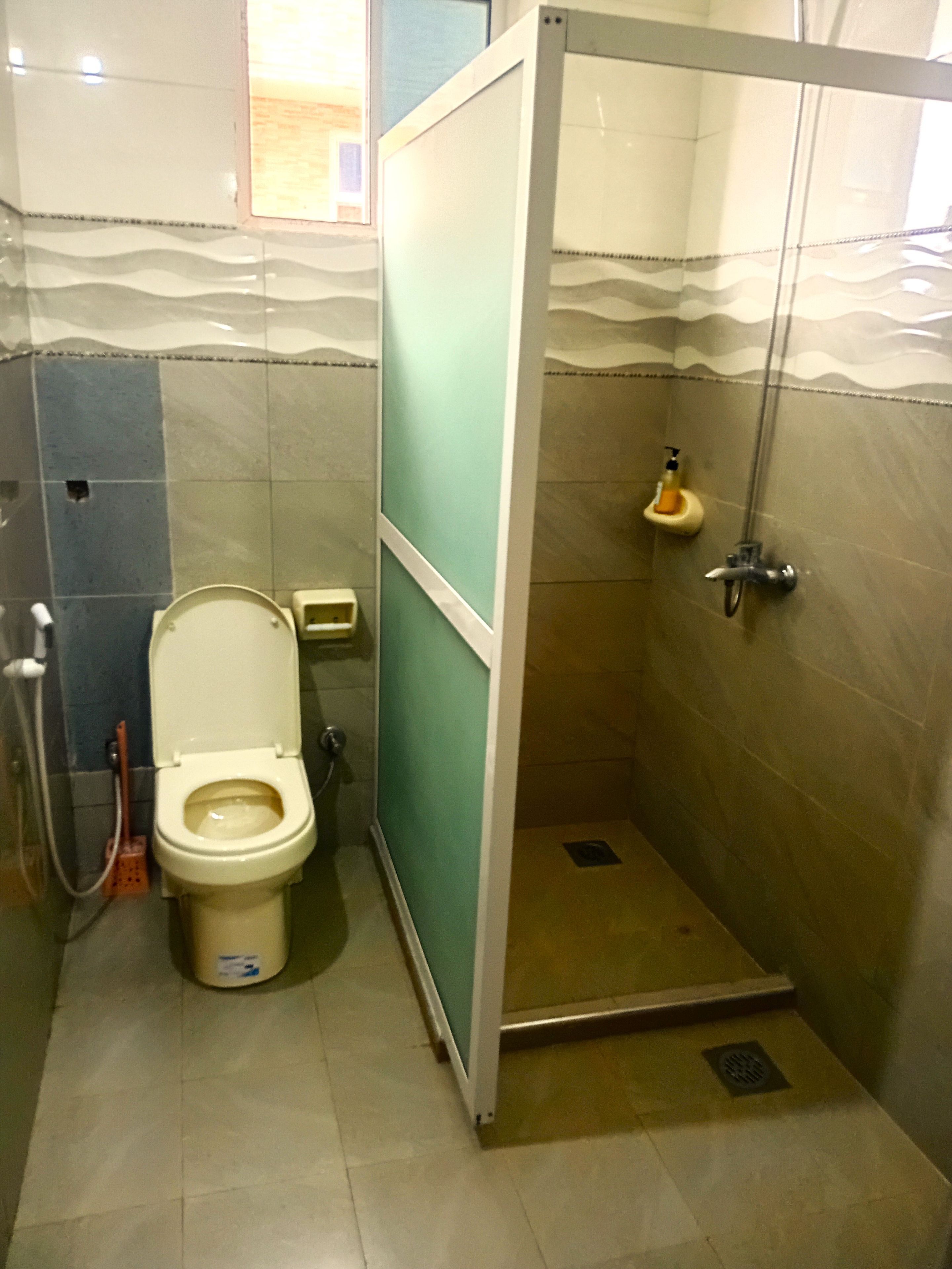 Un baño con inodoro, cabina de ducha y lavamanos.