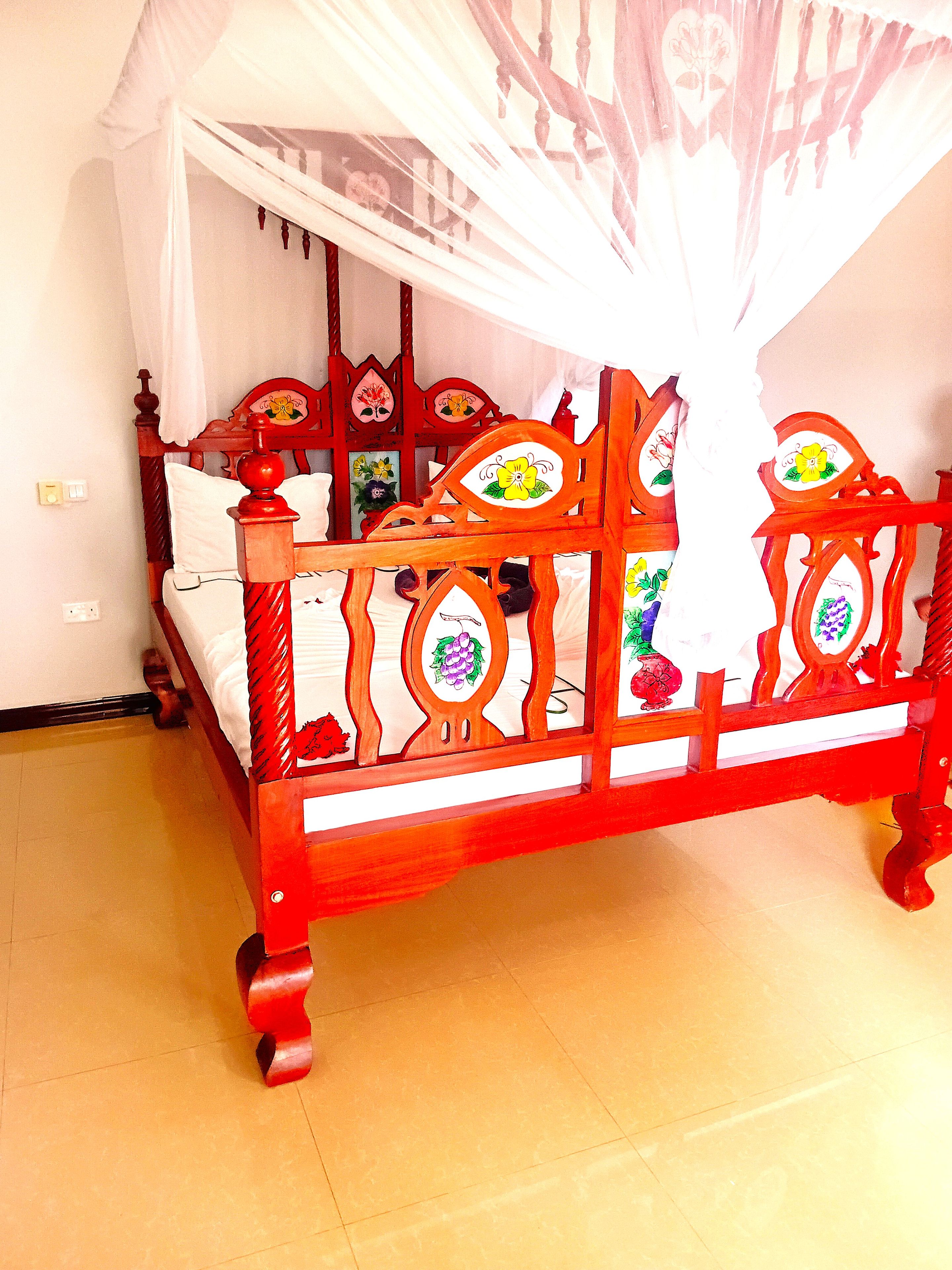 Una cama de madera con dosel, una mesita de noche y un interruptor de luz en la pared.