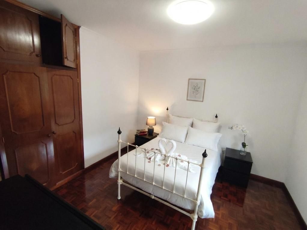 A bedroom with a bed, nightstand, lamp, and a wooden wardrobe.