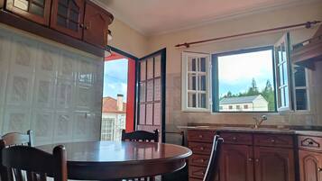 A kitchen with wooden cabinets, a dining table with chairs, and a window with a view of houses.