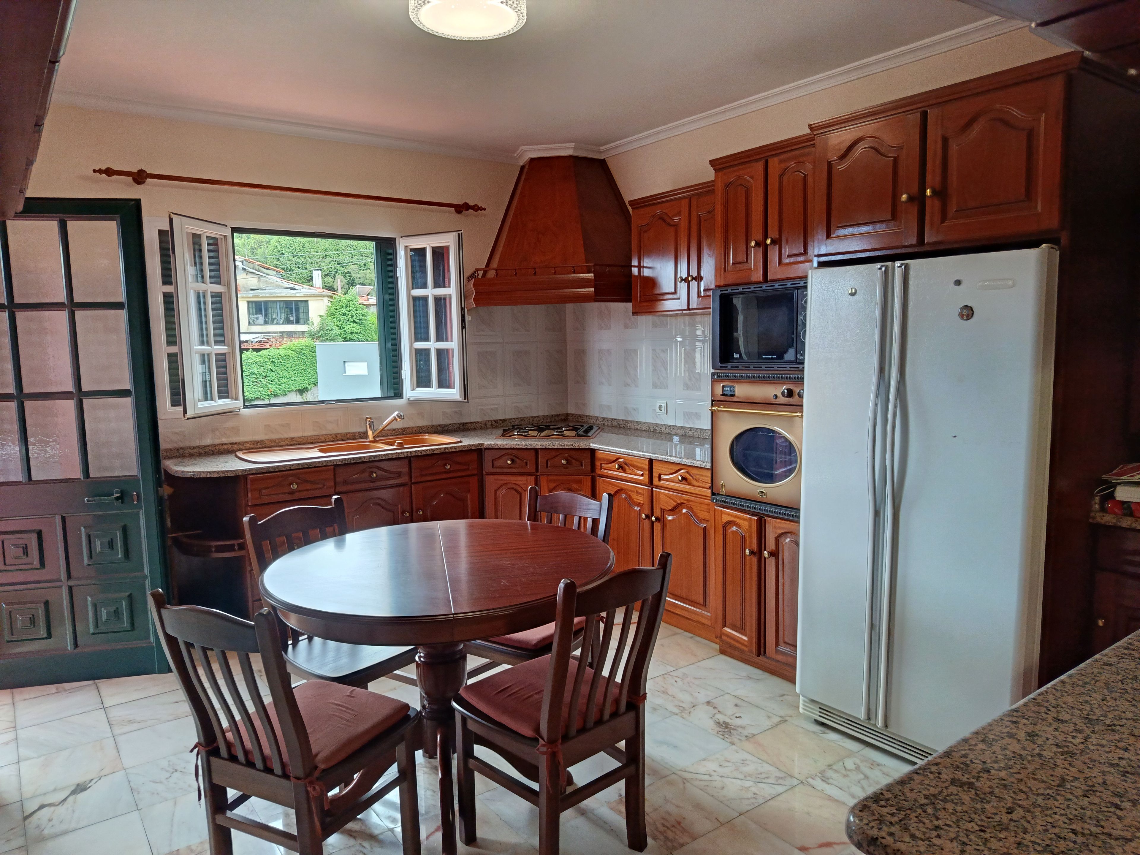 A kitchen with wooden cabinets, a built-in oven, a microwave, and a stainless steel refrigerator.