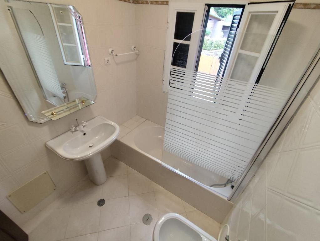 Un baño con lavamanos, espejo, cabina de ducha y retrete.