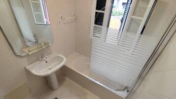 Un baño con lavamanos, espejo, cabina de ducha y retrete.