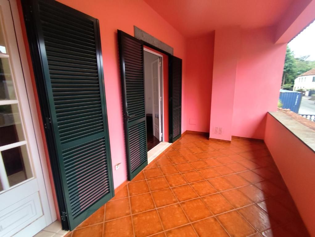 Un pasillo con piso de baldosas, una puerta con ventanal y una pared rosa.