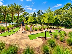 A miniature golf course with a man and a child playing, surrounded by lush greenery and trees. - Luxurious Retreat 3Beds/2Baths with Club Access (Davenport)