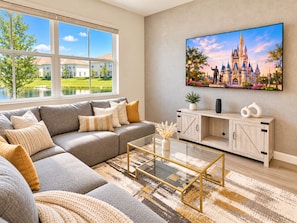 A modern living room with a sectional sofa, a coffee table, and a flat-screen TV mounted on the wall. - Luxurious Retreat 3Beds/2Baths with Club Access (Davenport)