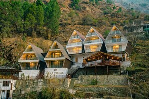 A hotel with multiple triangular-roofed buildings, a stone facade, and a sign reading 'RAJ VILLAS'. - Raj Villas by Jomotel, Riverside Retreat (Palach)