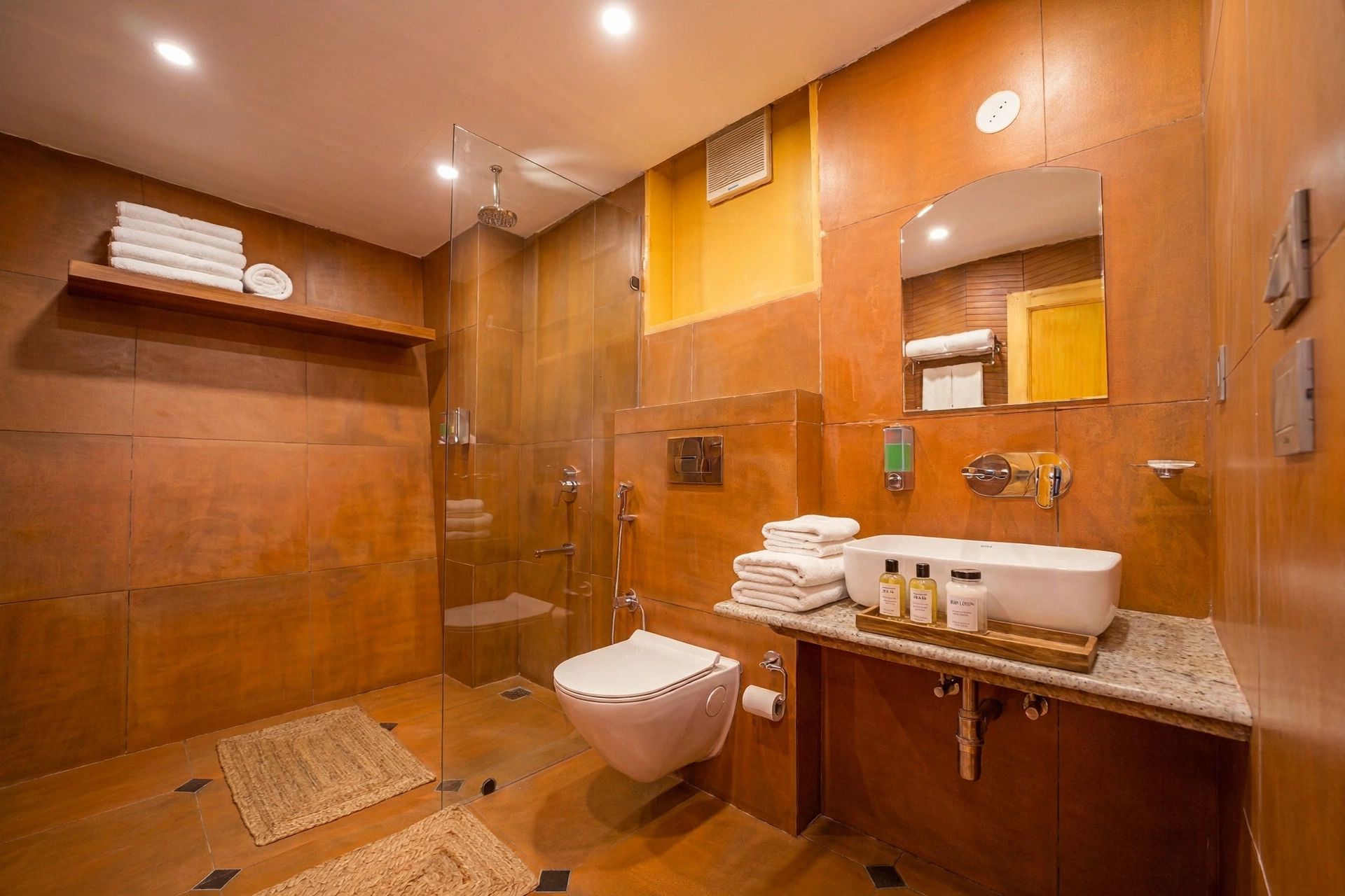 Een moderne badkamer met een douche met glazen wand, een wit toilet en een wastafel met toiletartikelen.