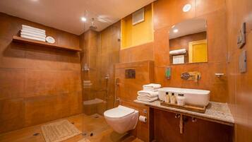 Een moderne badkamer met een douche met glazen wand, een wit toilet en een wastafel met toiletartikelen.