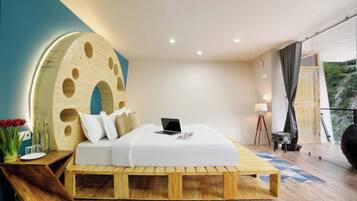 Een moderne slaapkamer met een bed op een houten platform, een laptop op het bed en een grote ronde wanddecoratie.