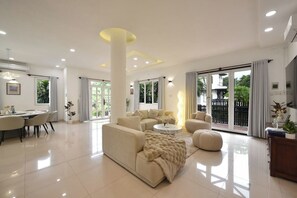 A spacious living room with a sofa, coffee table, and dining area. - 6BR Pool Villa with Karaoke & Games Room, Thảo Điền, Sleeps 14 (Thành phố Hồ Chí Minh)