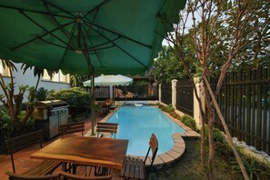 A backyard with a swimming pool, a barbecue grill, and a wooden table with chairs. - 6BR Pool Villa with Karaoke & Games Room, Thảo Điền, Sleeps 14 (Thành phố Hồ Chí Minh)