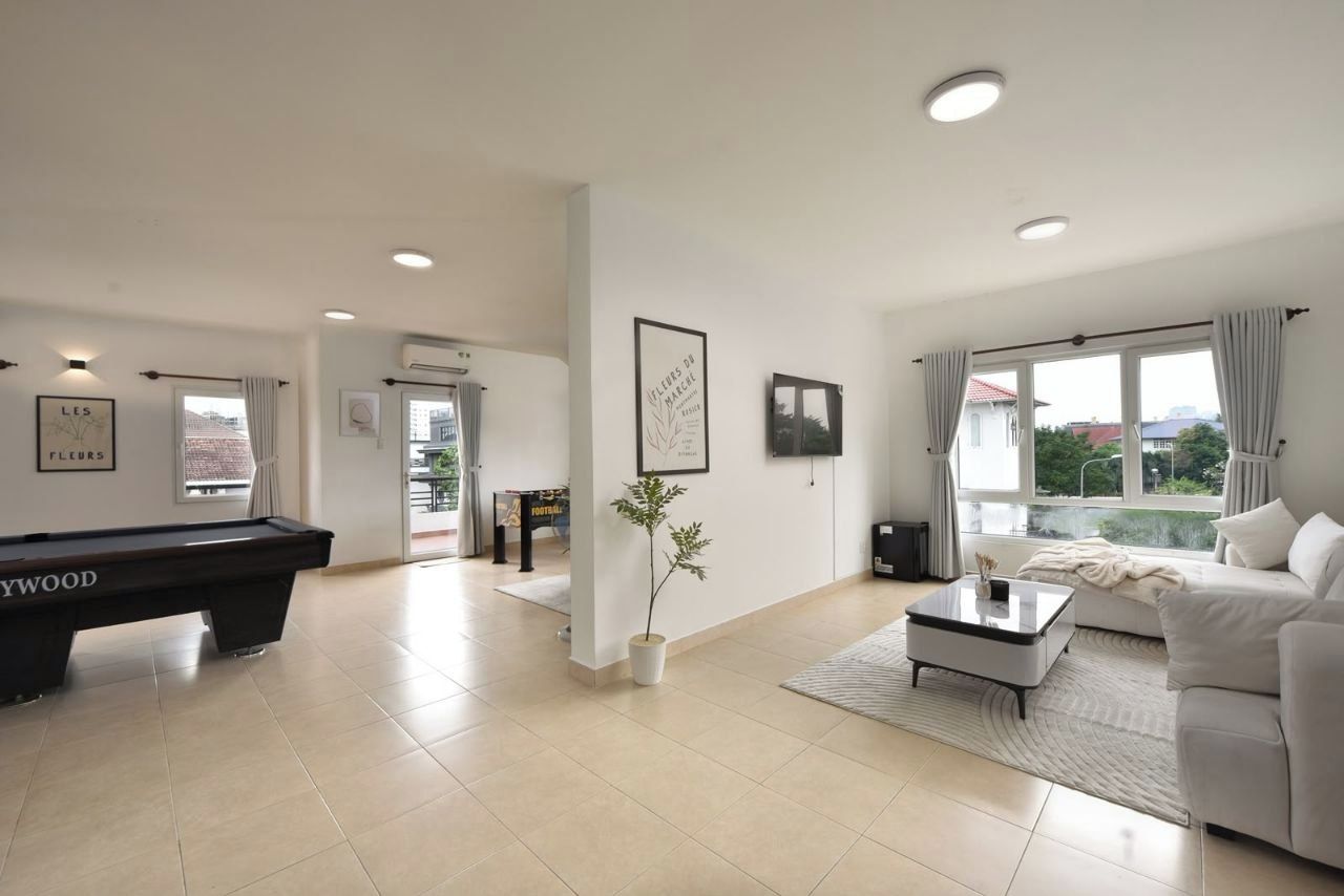 A modern living room with a pool table, a sofa, a coffee table, and a view of the outdoors.