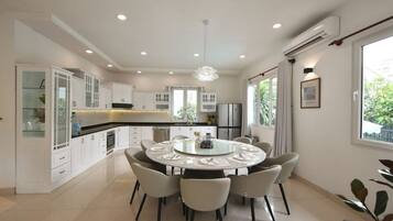 A modern kitchen with white cabinetry, a central island, and a dining area with a round table and chairs.