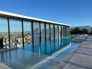 A rooftop infinity pool with a city view, surrounded by glass railings and outdoor seating. - 2BR West End Apt w/ Parking Walk to Convention Ctr (West End)