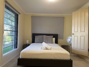 A bedroom with a bed, a window, a door, and a bedside table with a lamp. - Ormiston Bayside Family Stay with Private Pool (Ormiston)