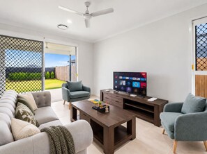 A modern living room with a sofa, armchairs, a coffee table, and a TV. - Spacious 4BR Family Home |Central Air-Con |Retreat (Pallara)