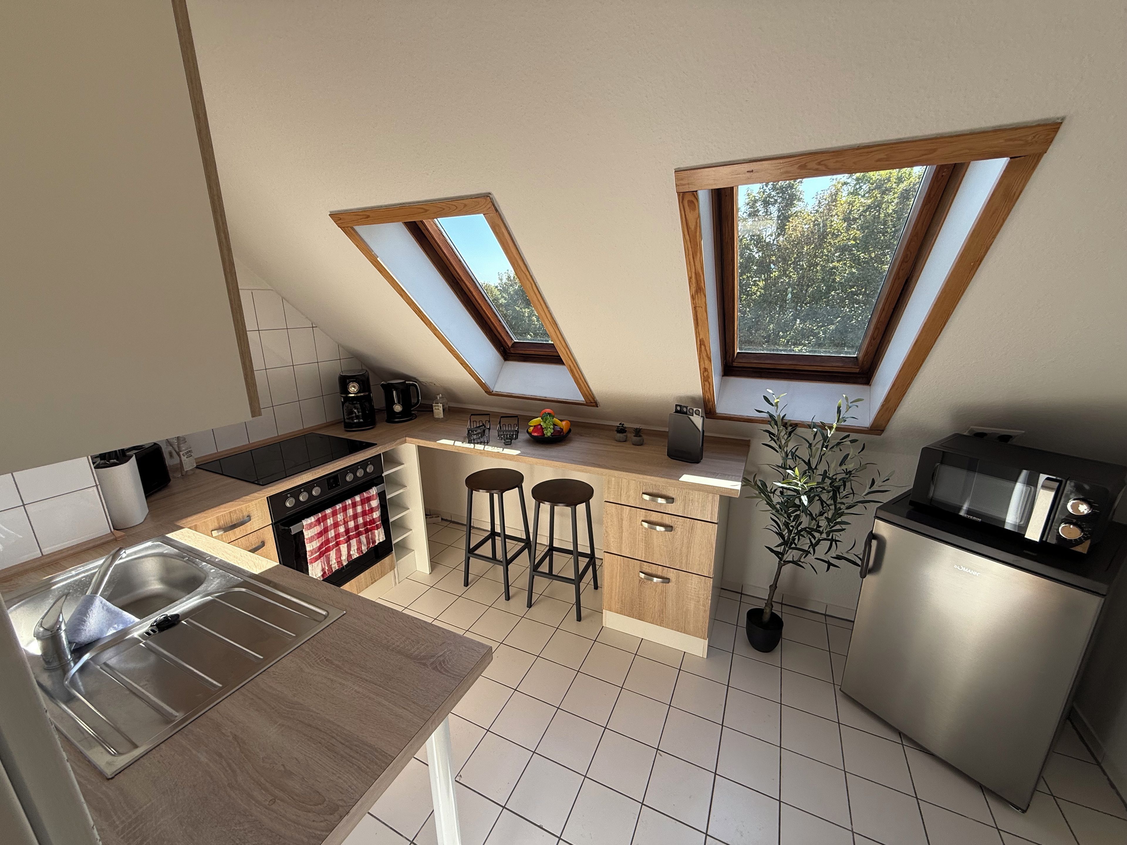 Een moderne keuken met dakramen, een spoelbak, een fornuis, een magnetron en een klein barretje.