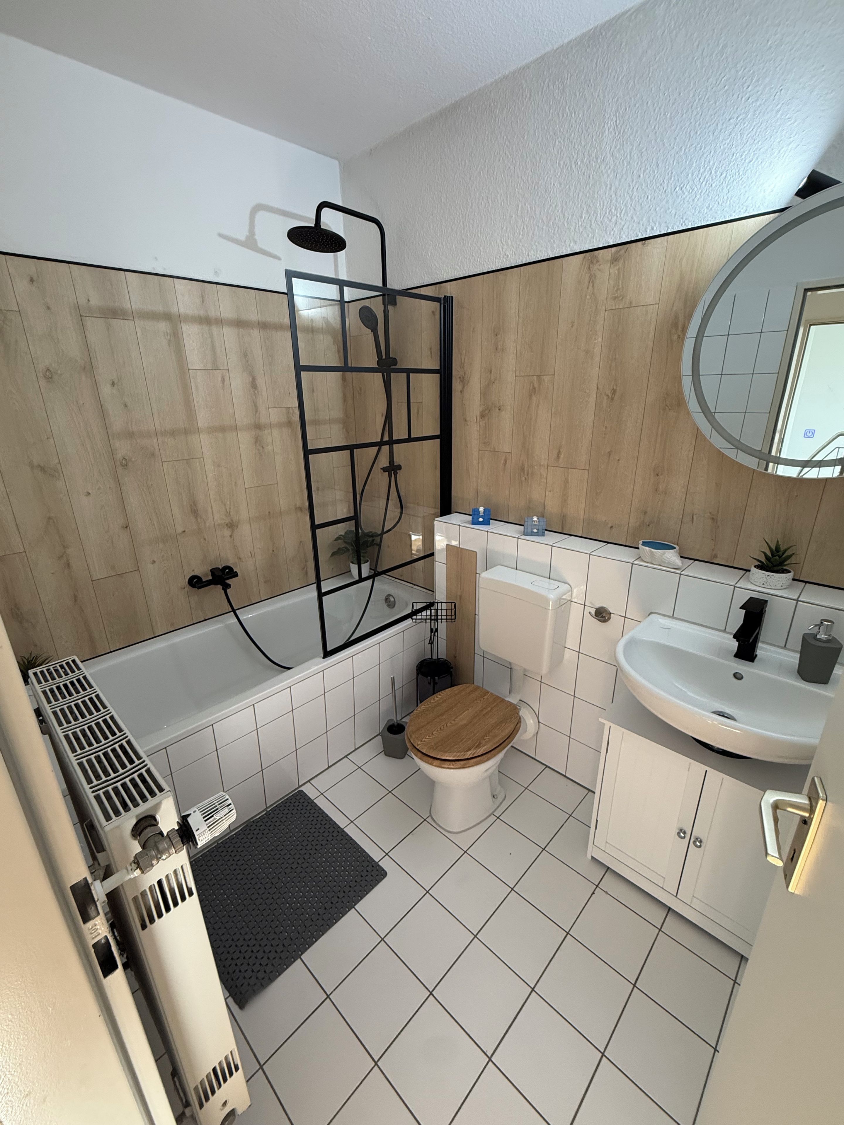 Un baño moderno con cabina de ducha, inodoro, lavabo y espejo.