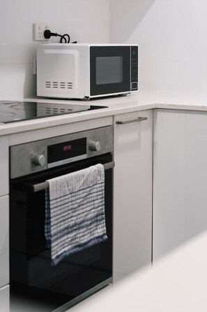 A kitchen with a microwave, oven, and a towel hanging on the oven handle. - Brisbane City Studio |Central | Walk to Everything (Petrie Terrace)