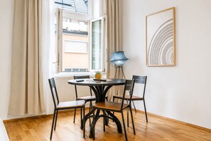A dining area with a round table, four chairs, a lamp, and a framed artwork on the wall. - Vienna Vibrant Center | Comfortable 2BR Apartment (Wien)