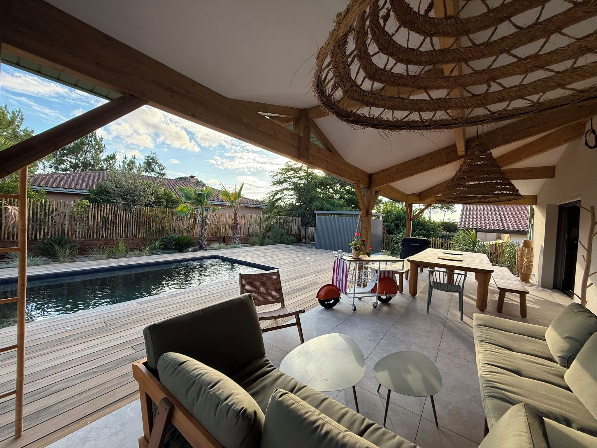 Un espace extérieur aménagé en terrasse, avec une plateforme en bois, une piscine et des coins salon.