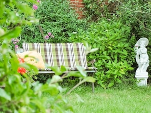 Ein Garten mit einer Bank und einer Statue.