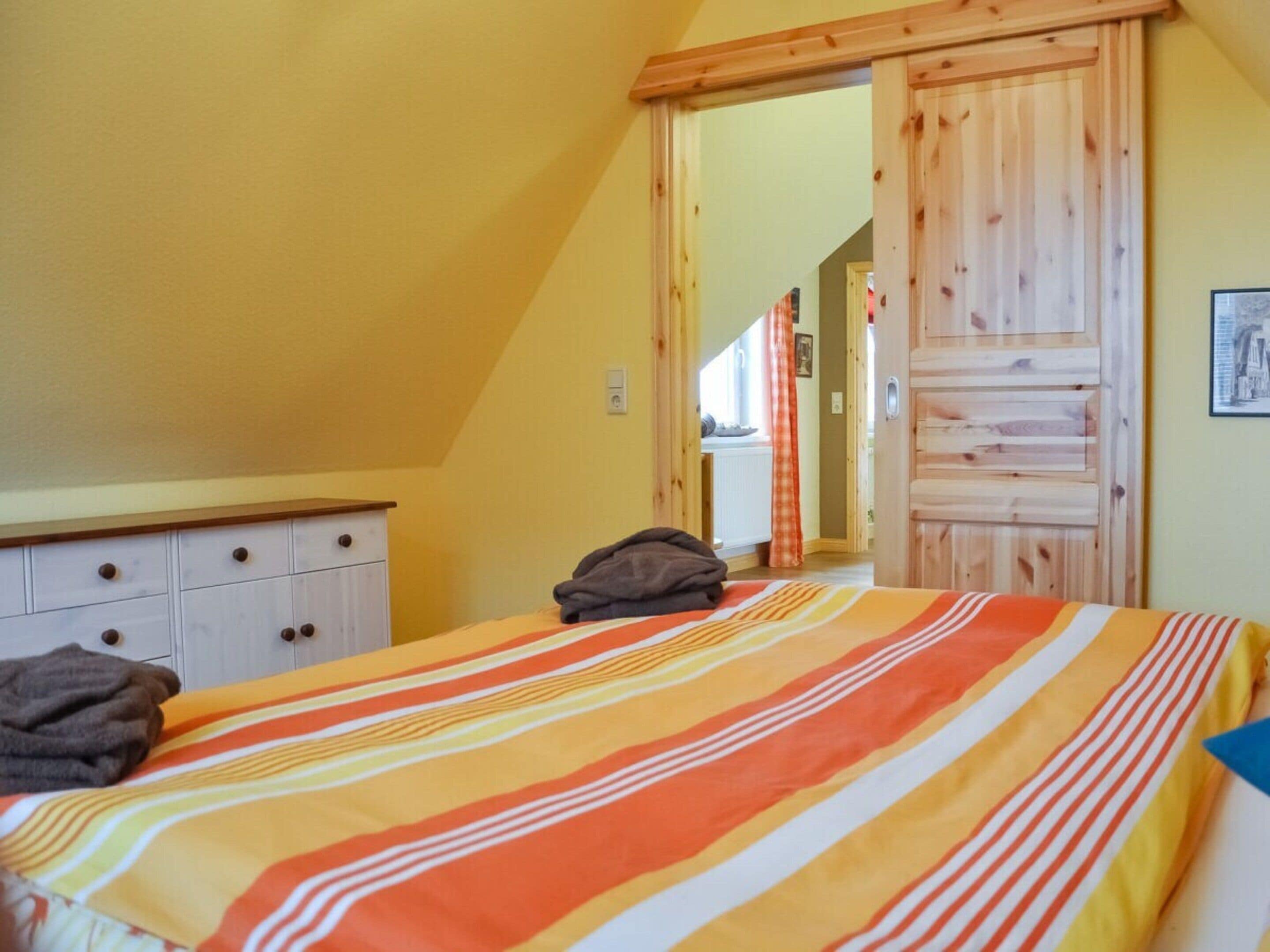 Une chambre à coucher avec un lit, une armoire en bois et une porte donnant sur une autre pièce.