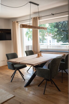 Ett modernt matområde med ett träbord, sex stolar och en hängande lampa.