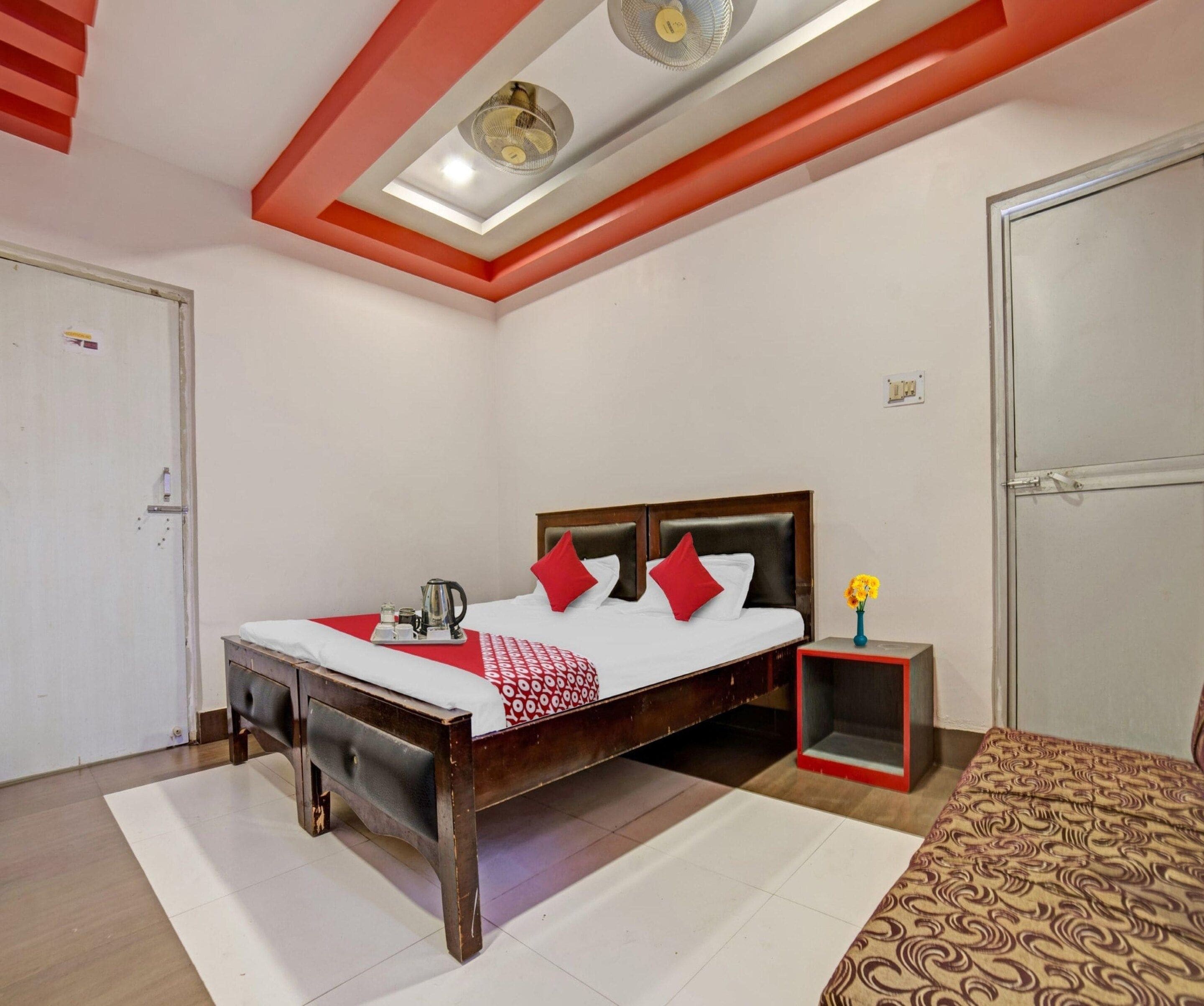 Una habitación de hotel con cama, mesita de noche y una pequeña mesita con un florero.