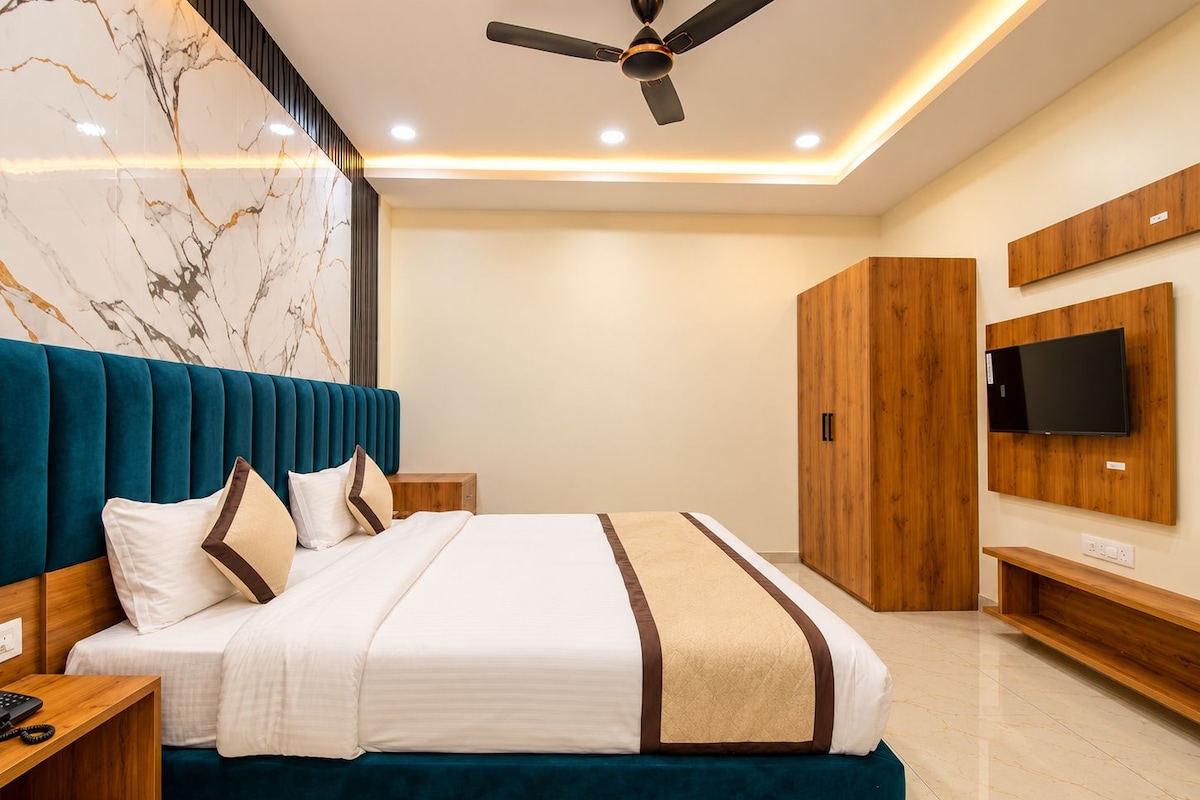 A modern bedroom with a bed, a ceiling fan, a TV mounted on the wall, and a wooden wardrobe.