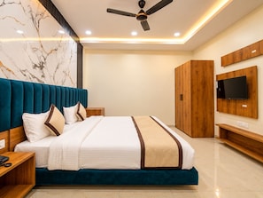 A modern bedroom with a bed, a ceiling fan, a TV mounted on the wall, and a wooden wardrobe. - Hotel D3 And Rooftop Mansarovar Jaipur (Jaipur)