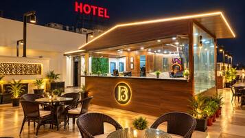 Un espace d’accueil d’hôtel avec un comptoir, des sièges et une vue sur le paysage urbain illuminé la nuit.